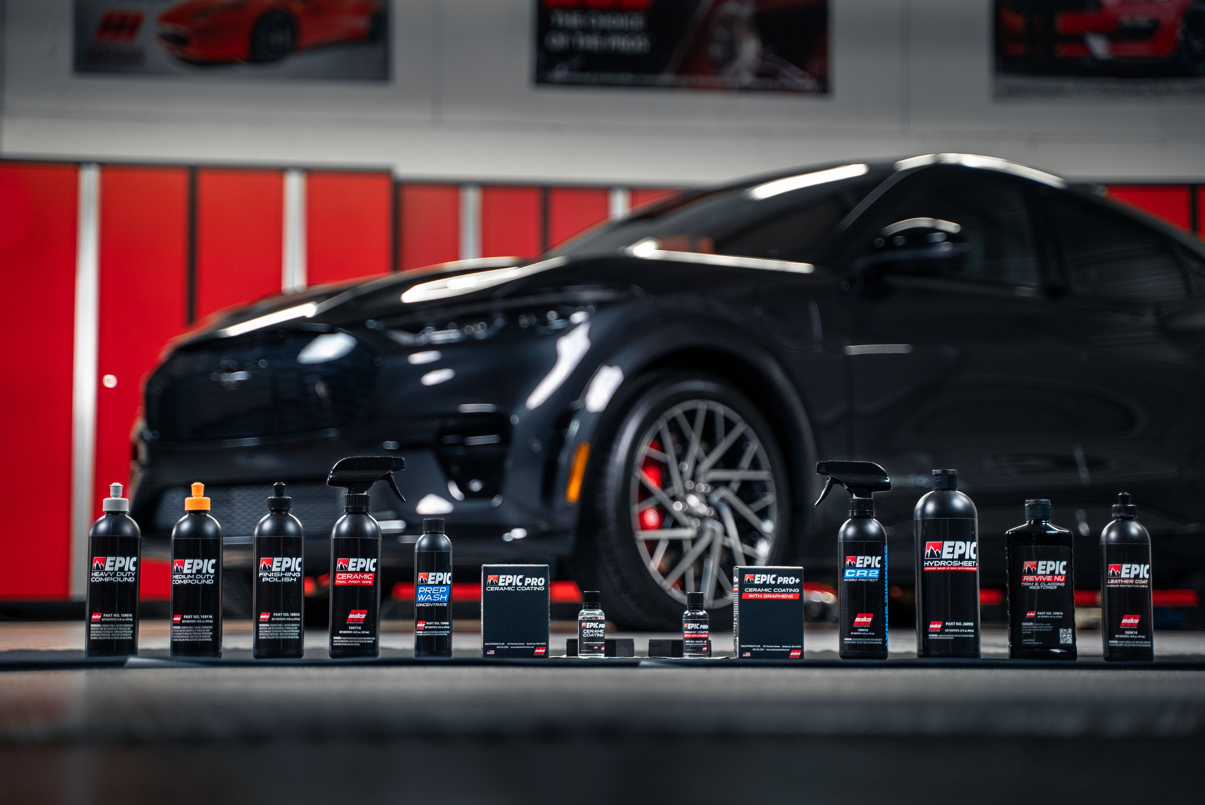 A row of bottles of cleaning products in front of a car (The Malco® EPIC® product lineup)