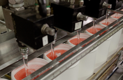 A machine with several buckets of liquid is present on the manufacturing line.