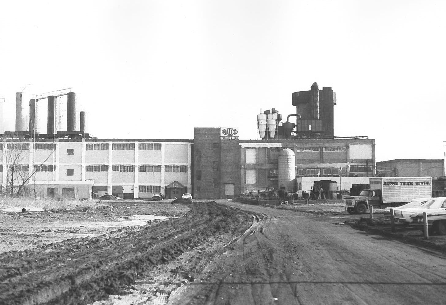 a dirt road leading to a factory