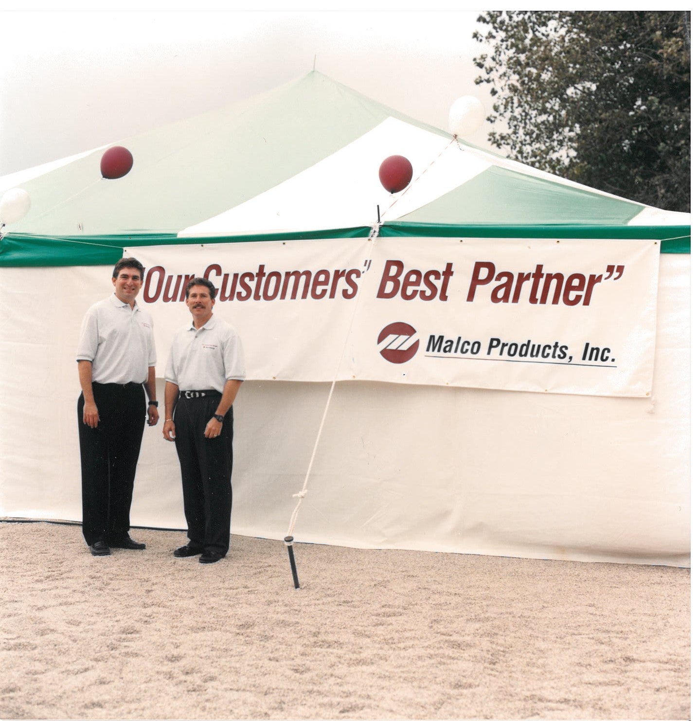 Two men are standing in front of a tent with the text on the image saying: "Our customers' Best Partner" - Malco Products, Inc.