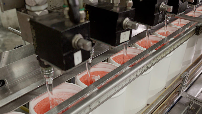 A machine with several buckets of liquid is present on the manufacturing line.